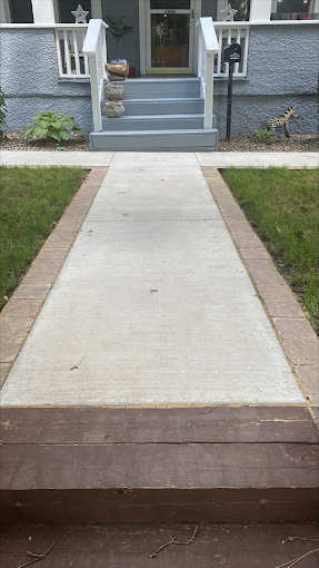 A concrete walkway leading to the front door of a house.