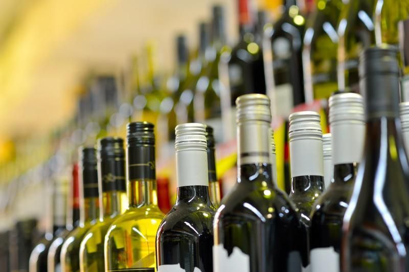 Rows of wine bottles in a shop, with colorful labels and blurred background shelves.