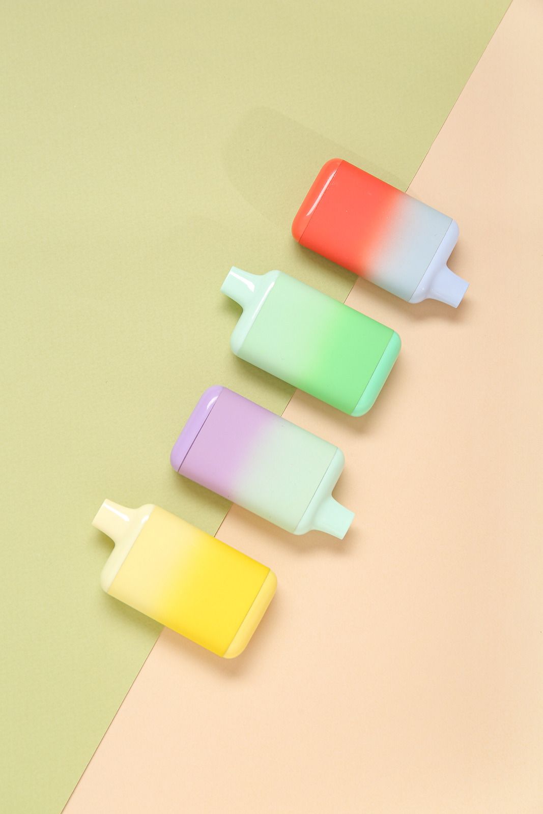 Four pastel-colored popsicle-shaped objects on a diagonal split green and beige background