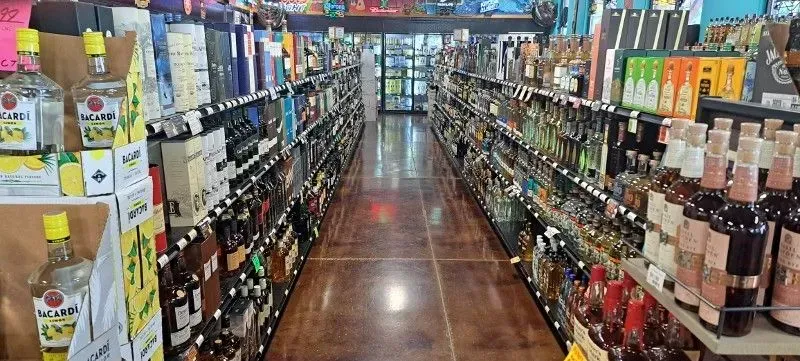 Aisle of a liquor store with shelves of bottles on both sides and a polished wooden floor