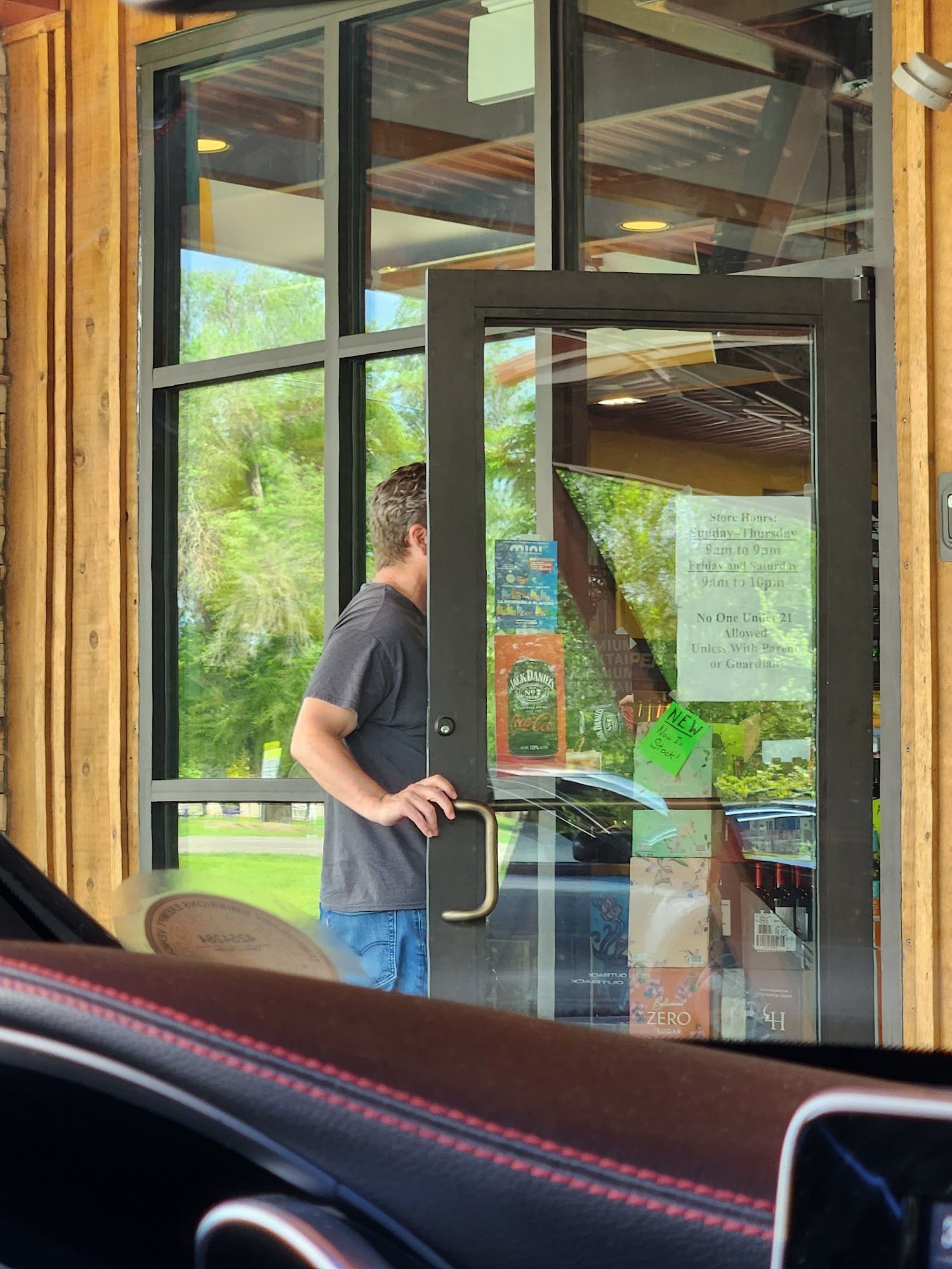 Person opening a glass door at a café entrance, seen from inside the car.
