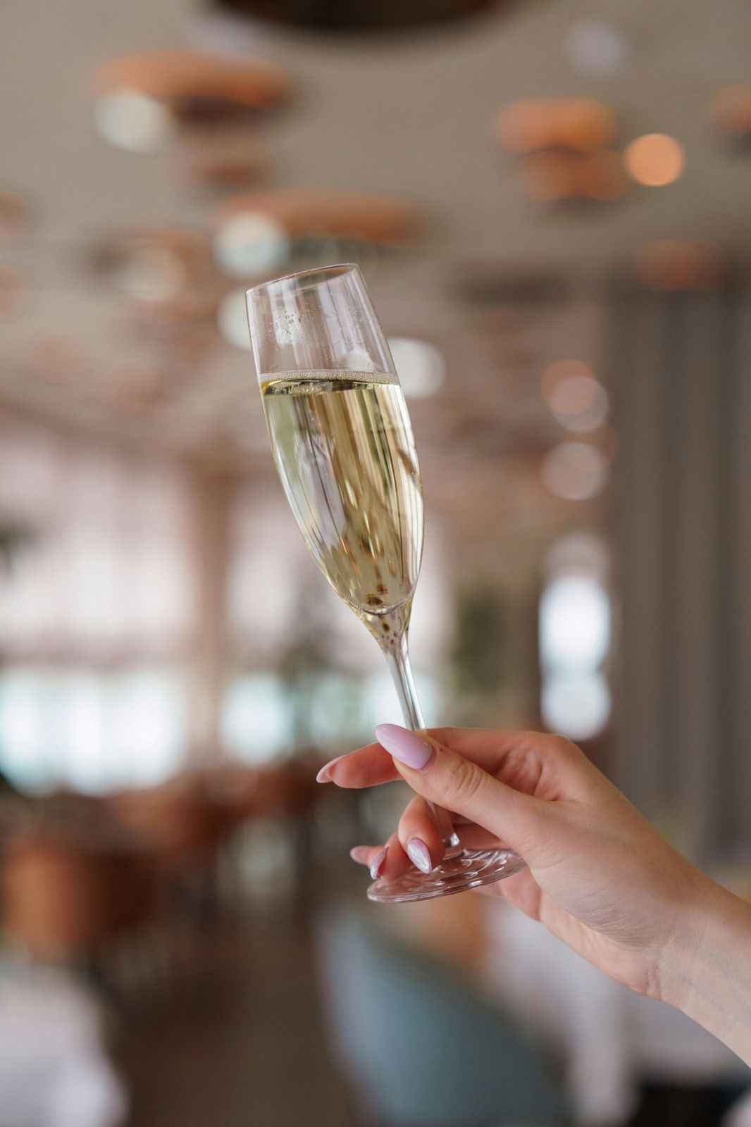 Hand holding a champagne flute in a softly lit indoor setting