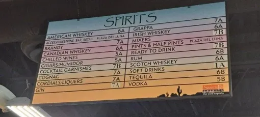 Handwritten spirits menu board with drink names and prices in pink and black on a light background