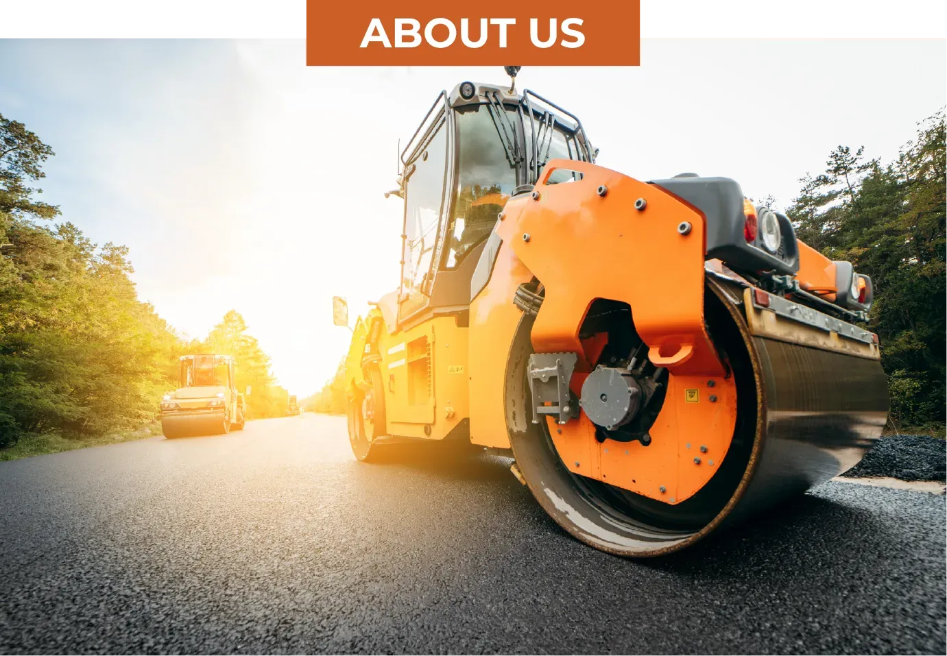 Orange road roller flattening fresh asphalt on a sunny road, with a smaller vehicle in the background.