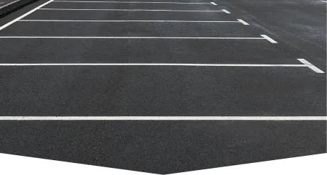 Empty parking lot with asphalt pavement and white painted lines marking individual parking spaces.