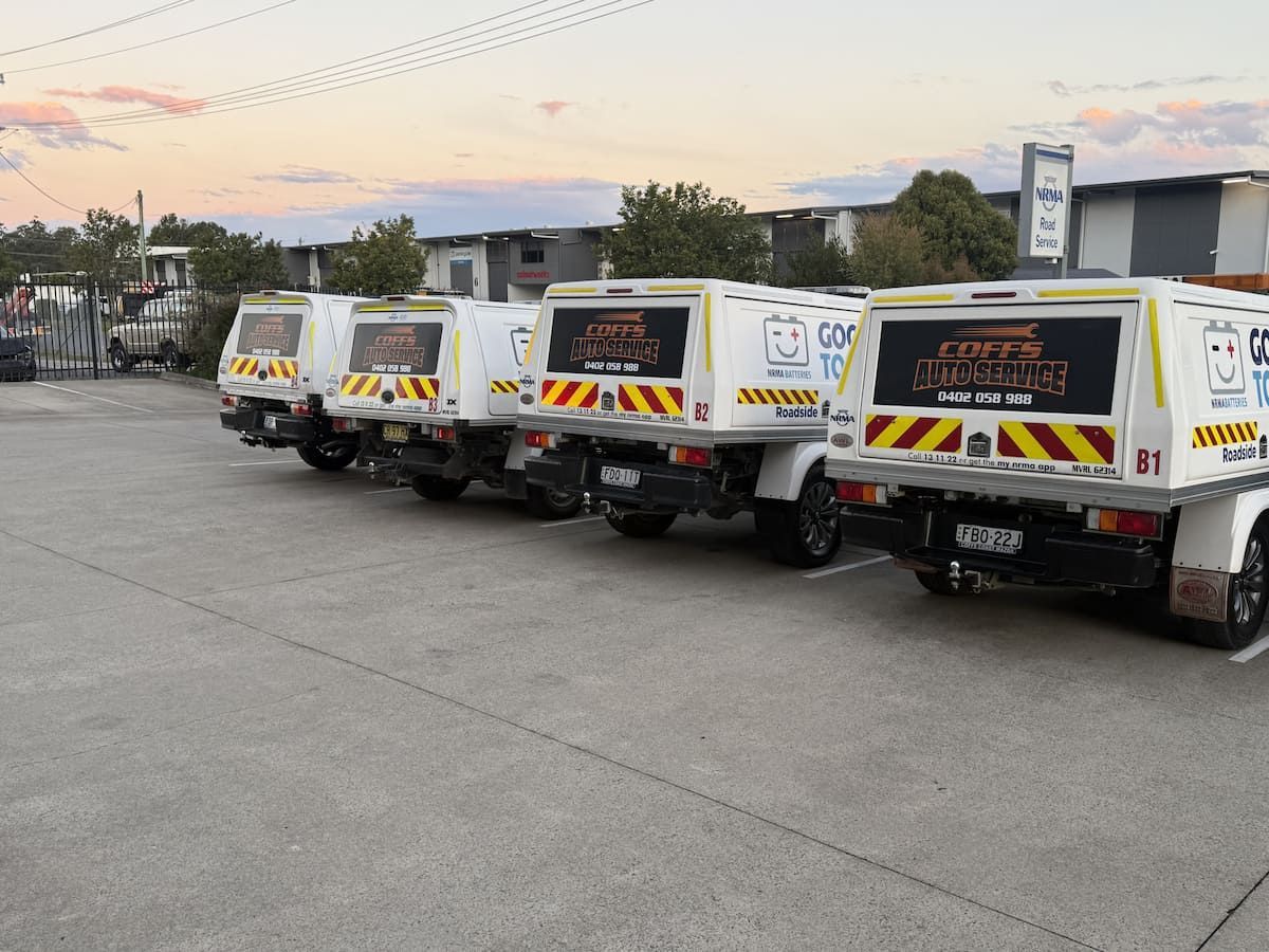White Utility Trucks Parked in a Row on a Concrete Lot at Sunset — Coffs Auto Service in North Boambee Valley, NSW