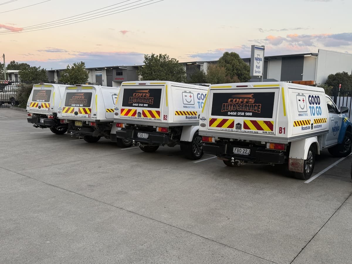 Several Small White Utility Vans Parked in a Row on a Concrete Lot at Dusk — Coffs Auto Service in North Boambee Valley, NSW