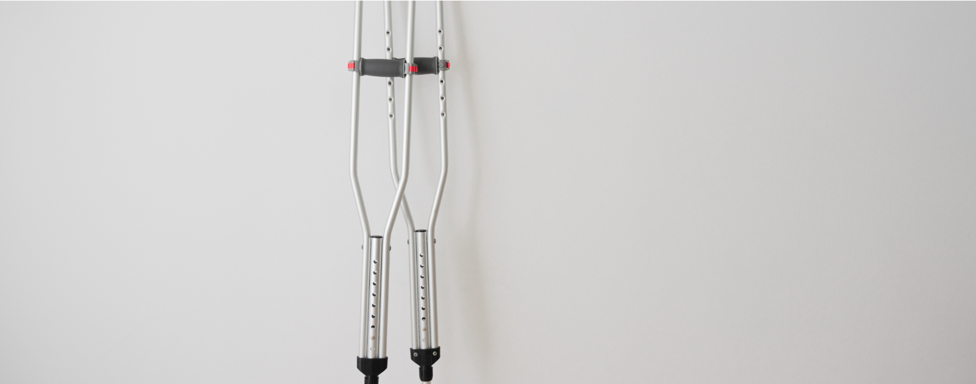 A pair of crutches are hanging on a white wall.