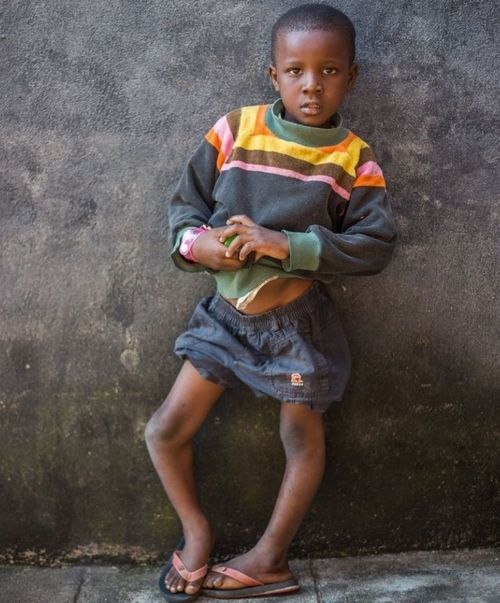 A young boy standing in front of a wall with his arms crossed