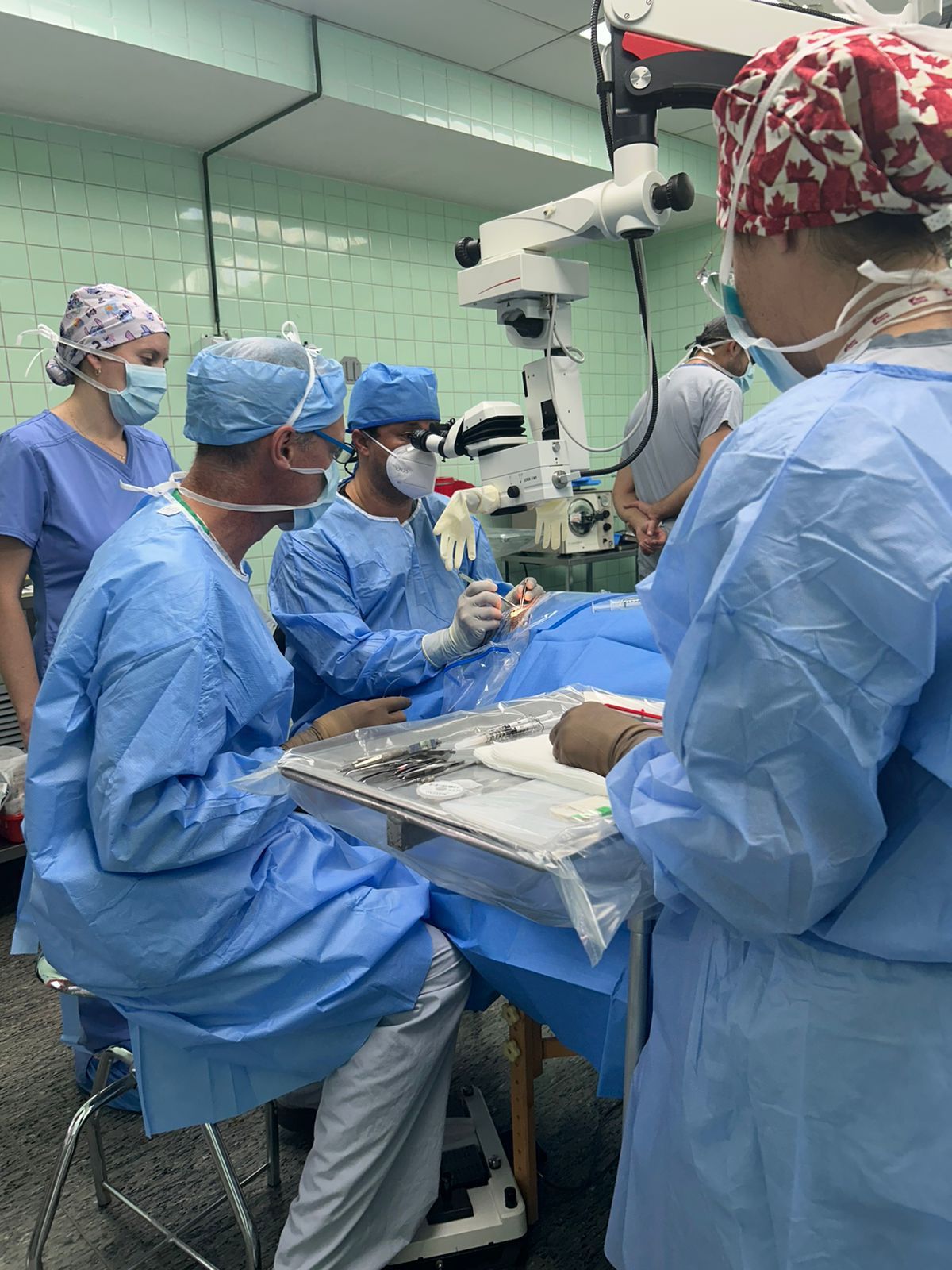 Cirujanos vestidos con uniformes azules realizan una cirugía ocular con un microscopio