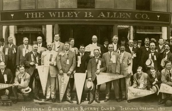 Un grupo de hombres posa para una foto frente al Wiley B Allen Co.