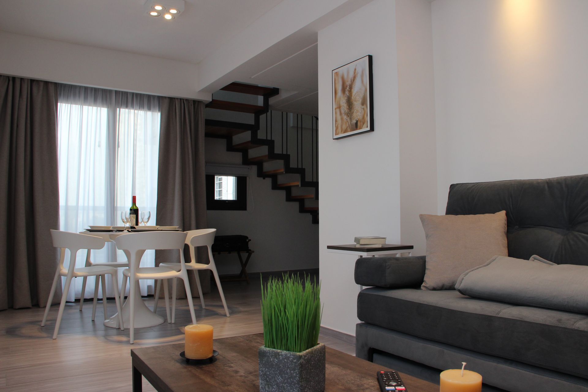 Modern living room with gray sofa, coffee table, dining area, and staircase in the background