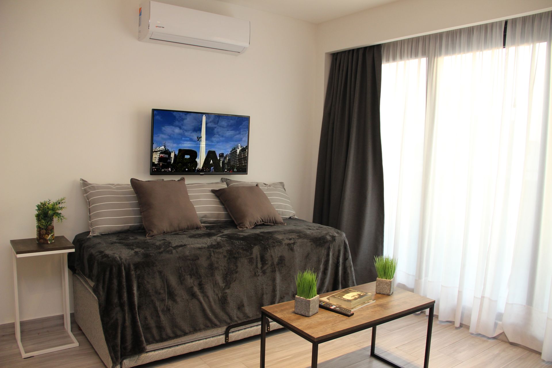 Modern bedroom with dark bedding, wall art, a white side table, and a coffee table near a bright sliding door