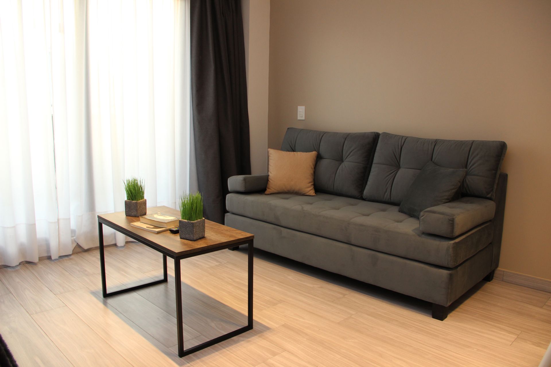 Modern living room with gray sofa, black coffee table, and floor-to-ceiling curtains near a window.