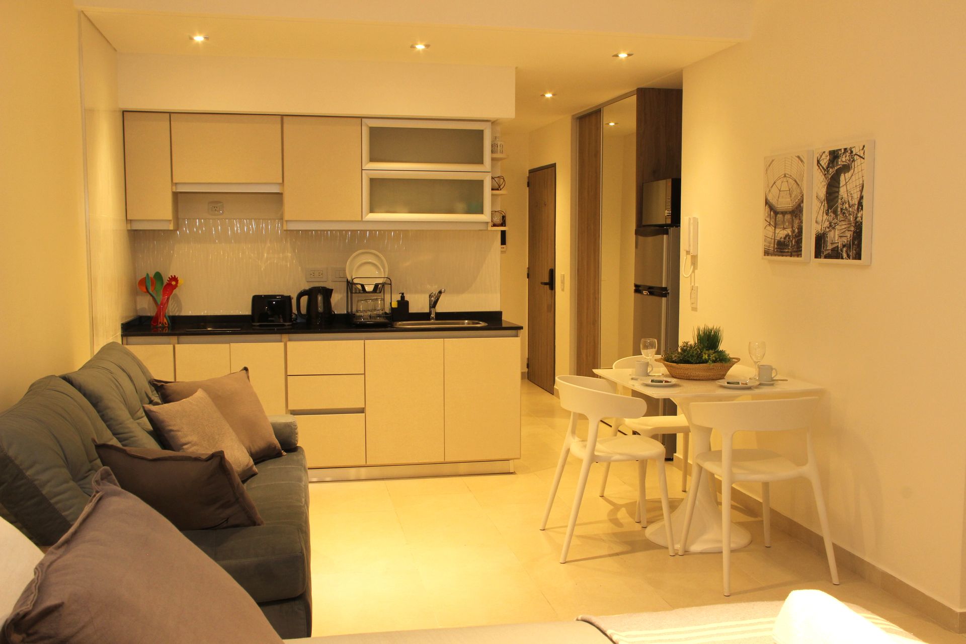 Warm open-plan living room and kitchen with beige sofa, dining table, and soft lighting