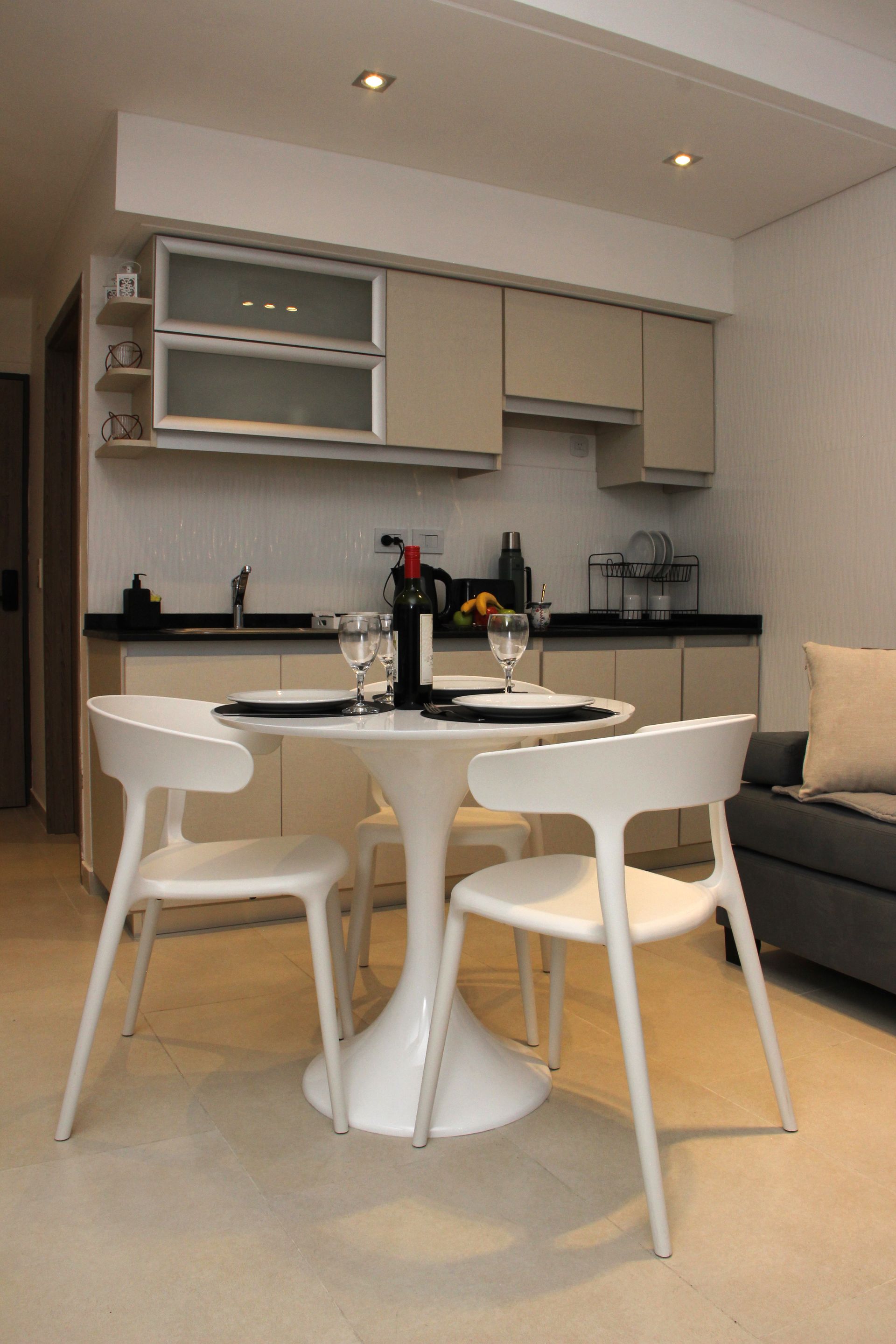 Modern kitchen nook with white chairs, round table, and beige cabinets in a bright apartment