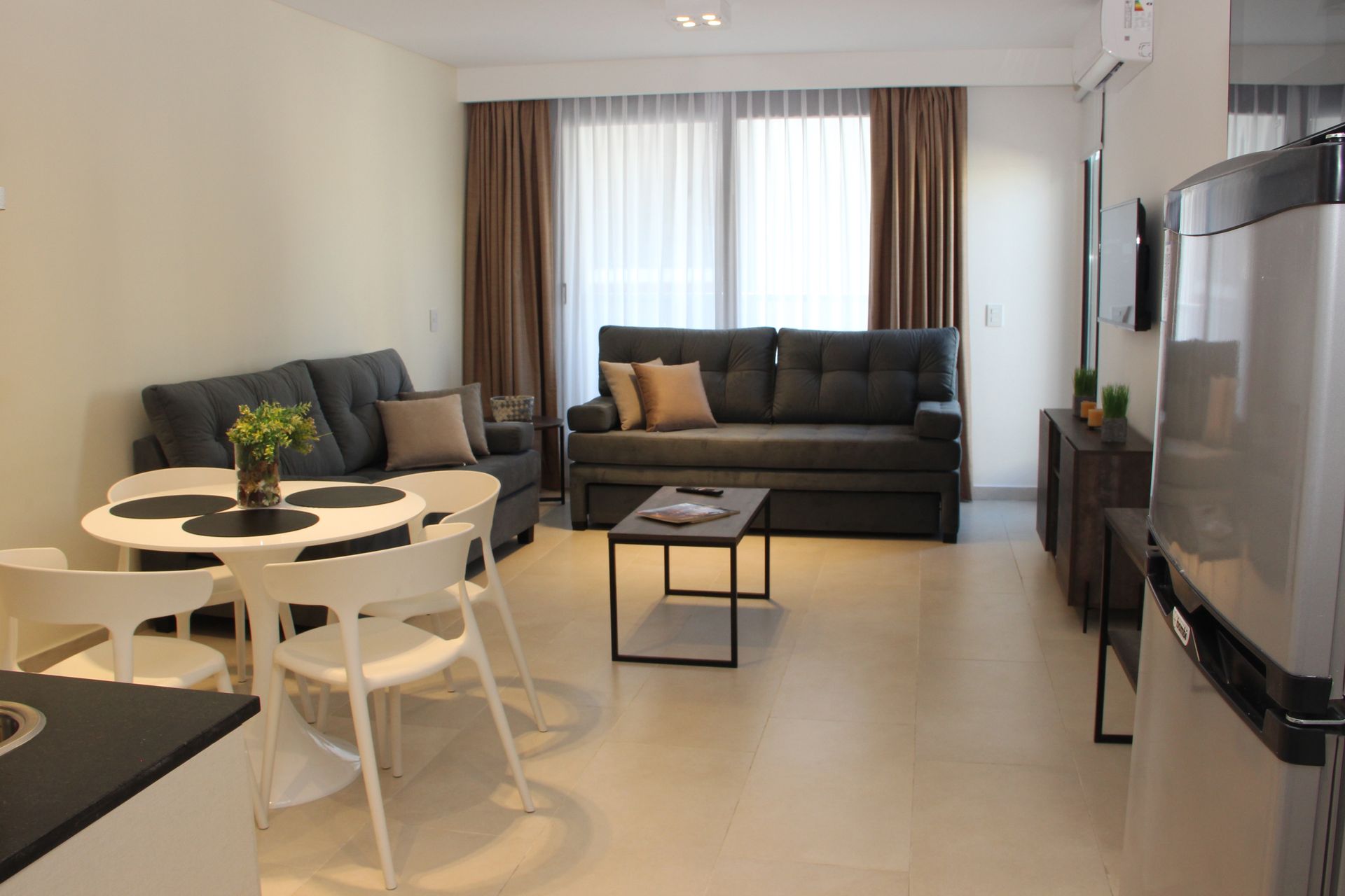 Modern living room with gray sofas, round dining table, coffee table, and large TV