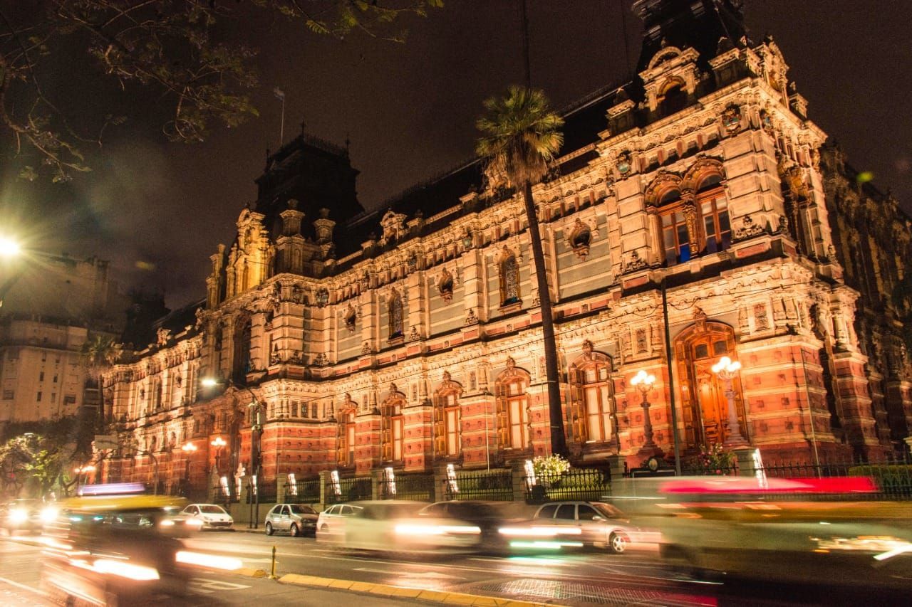 Night-lit ornate historic building with blurred car lights on a city street at dusk