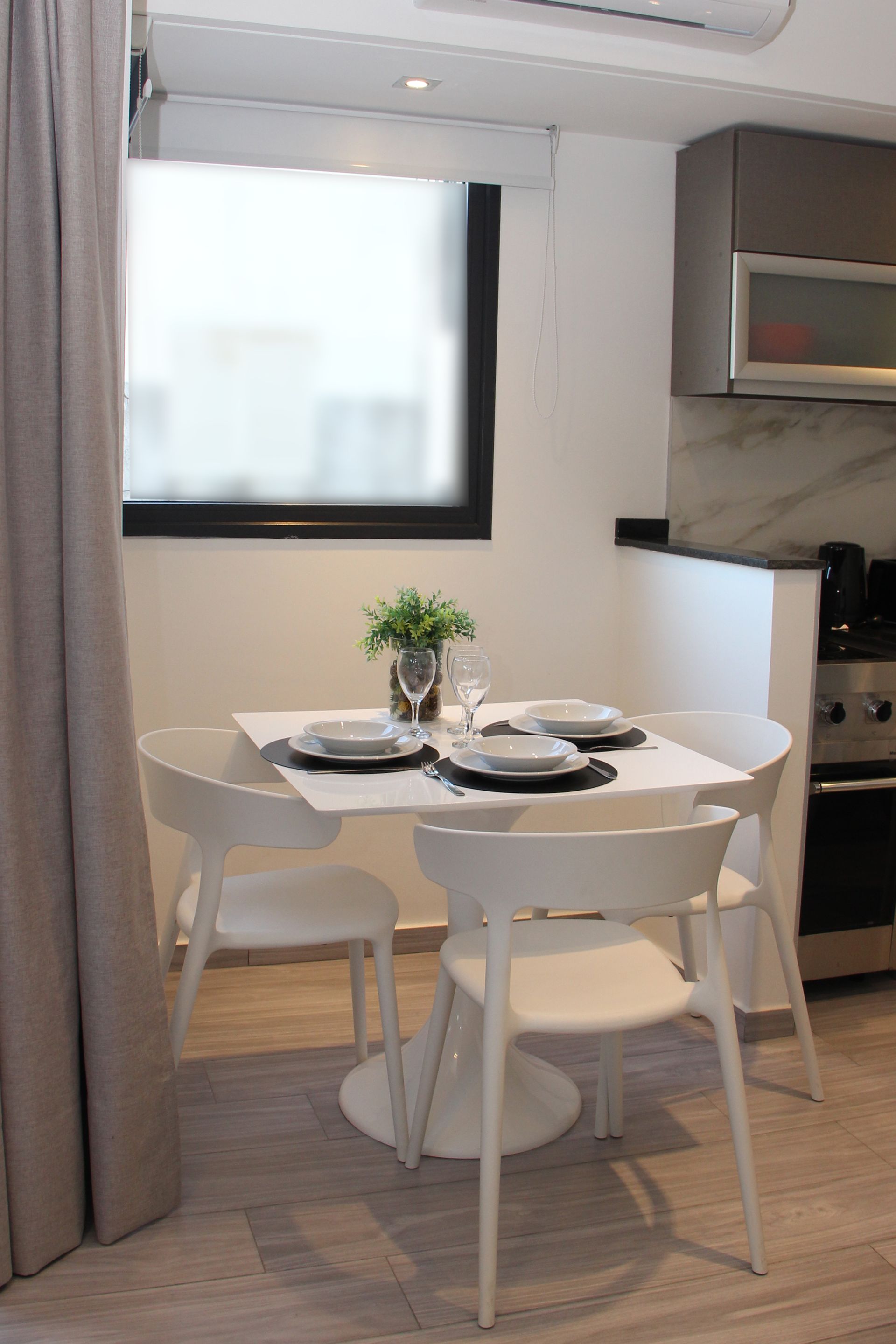 Small white dining table with four chairs in a modern kitchen nook near a window