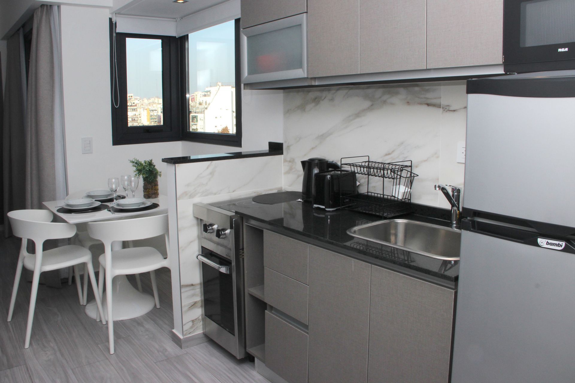 Modern gray kitchen with dining table, black countertop, and two chairs by a window