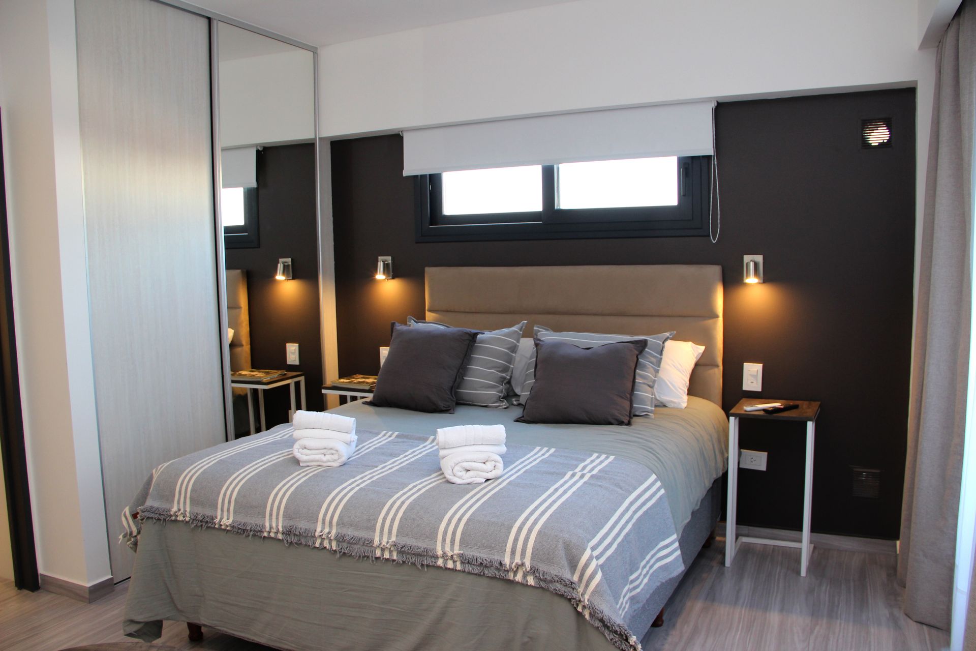 Modern bedroom with a gray bedspread, dark accent wall, and bedside lamps