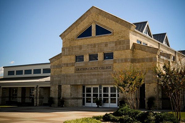 Grayson County College building on a sunny day; exterior with stone facade, entrance, and blue sky.