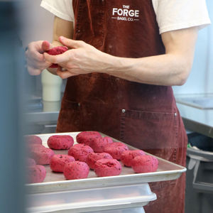 The Forge Bagel Team in brown aprons and white shirts stand in a cafe setting.