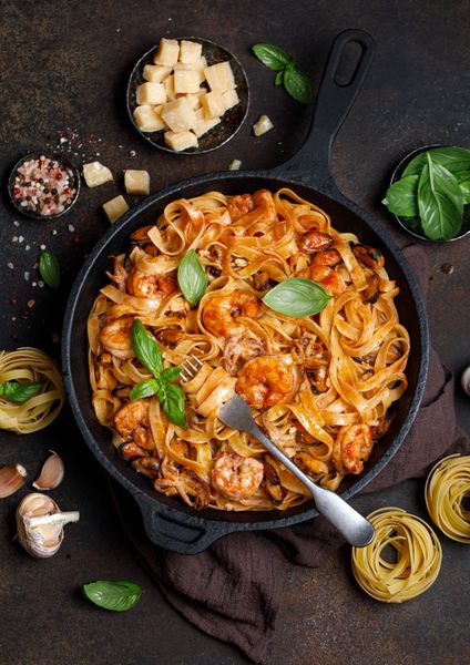 A pan filled with pasta and shrimp with a fork in it.