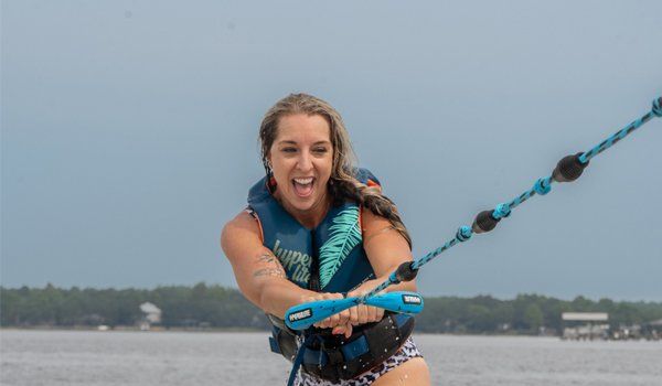 A woman in a life jacket is water skiing on a lake.