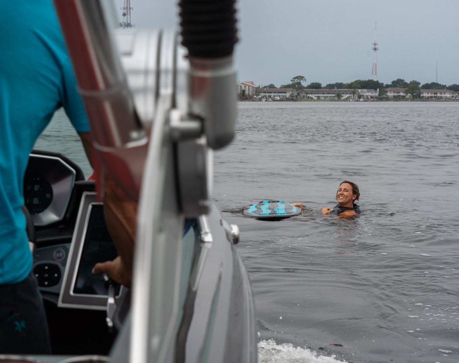A man is driving a boat with a woman in the water.