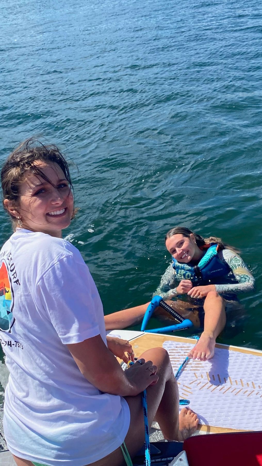 Two women are sitting on a boat in the water.