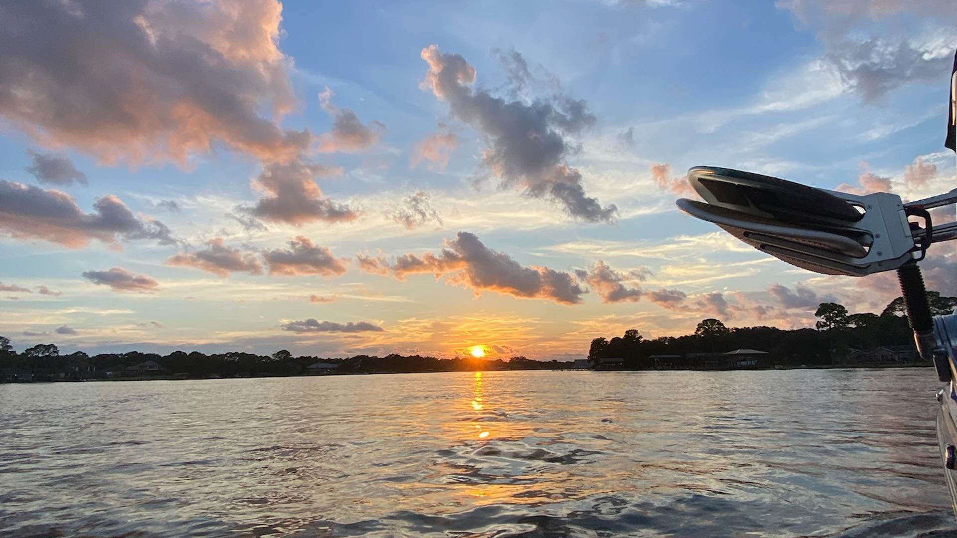 A sunset over a body of water with a boat in the foreground.