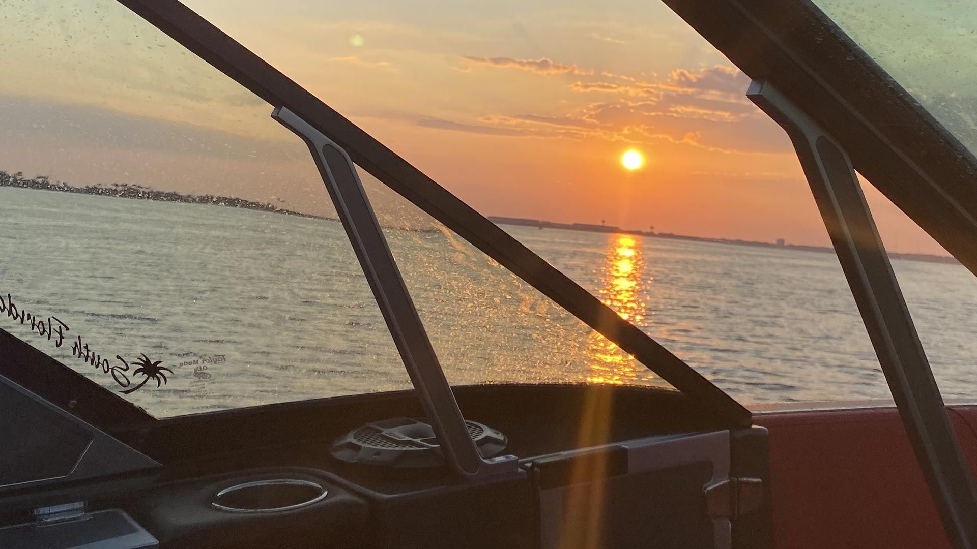 The sun is setting over the ocean from a boat