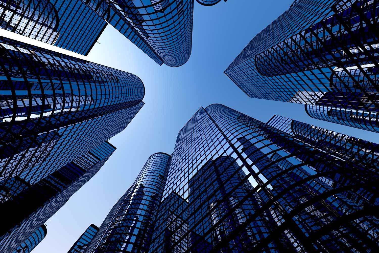 Low-angle shot of tall skyscrapers reaching towards a clear blue sky; glass facades reflect sunlight. Low-angle shot of tall skyscrapers reaching towards a clear blue sky; glass facades reflect sunlight.