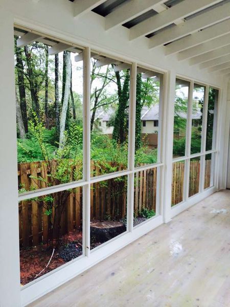 A room with lots of windows and a fence in the background