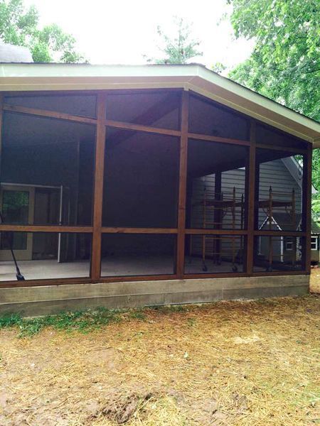 A screened in porch with a lot of windows on the side of a house.