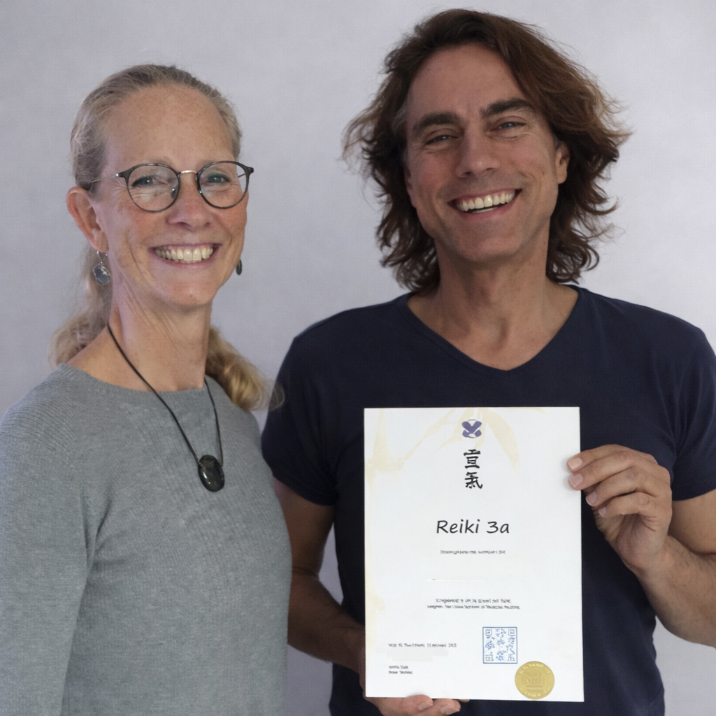 Een Reiki Master en een cursist laten lachend een certificaat zien.