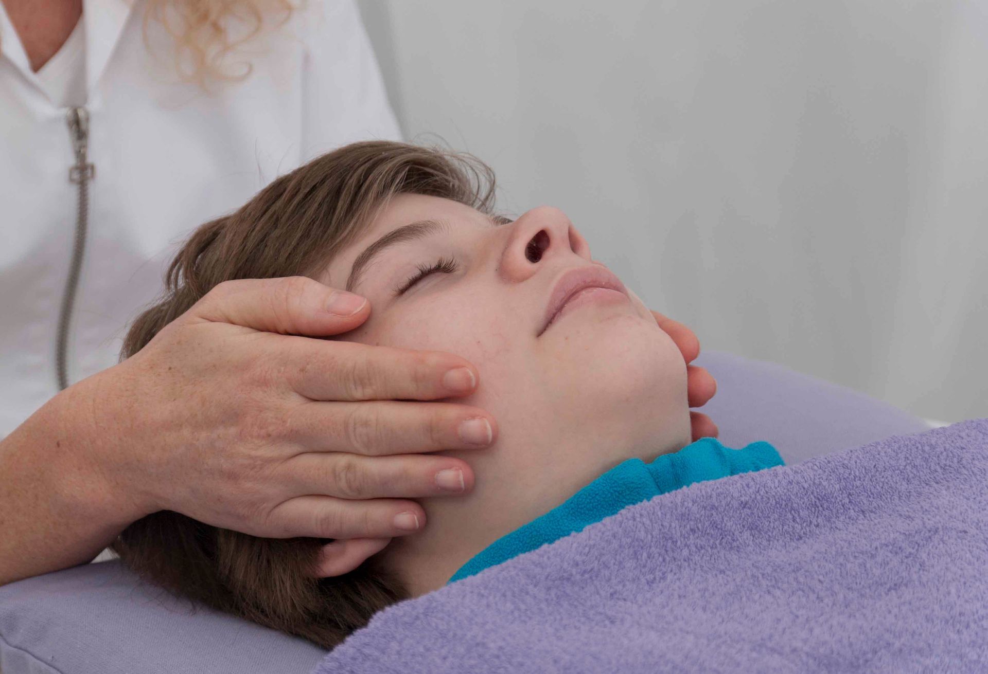Liggend kind wordt met Reiki behandeld op het hoofd.