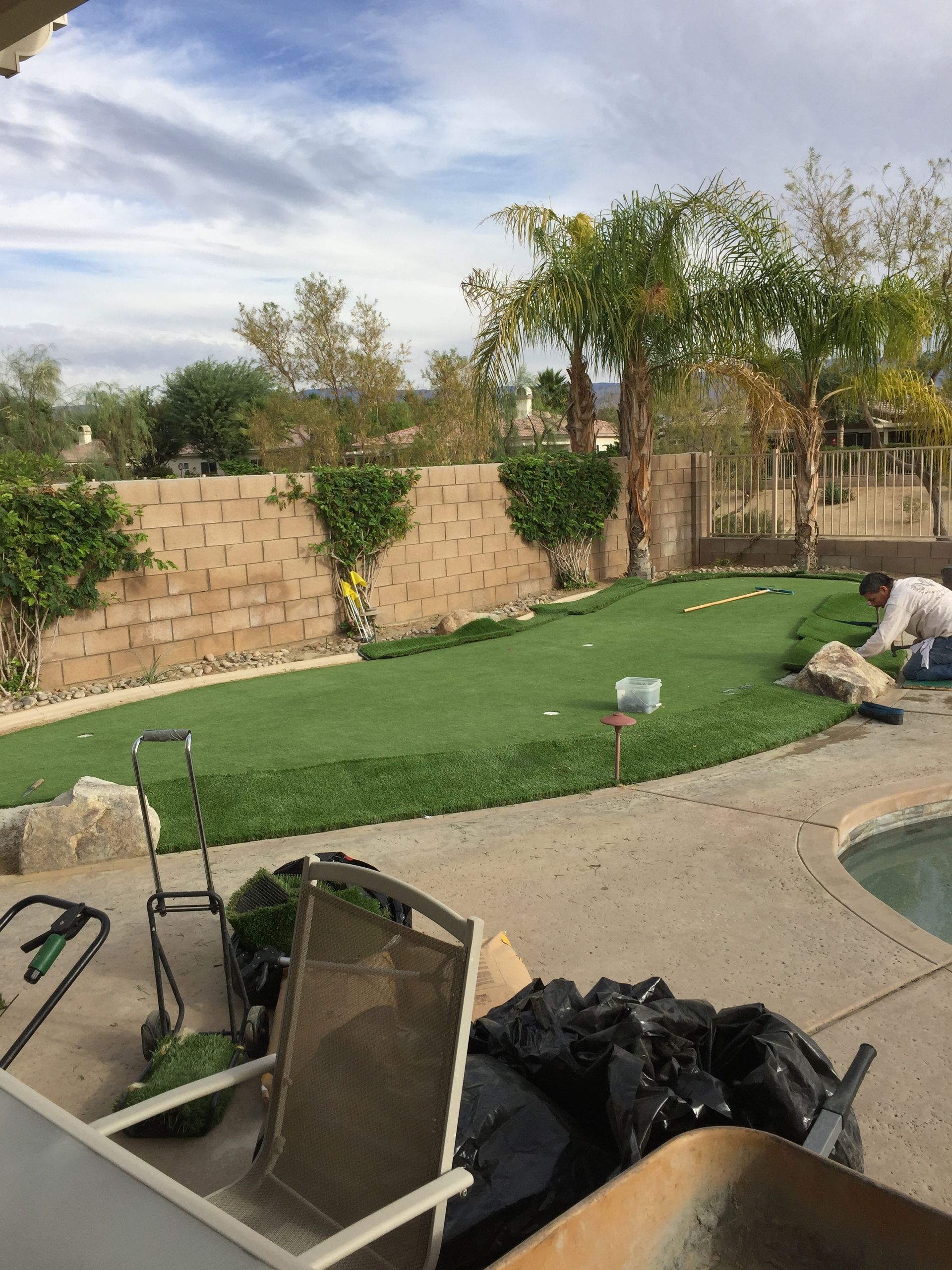 A man is working on a lawn next to a pool