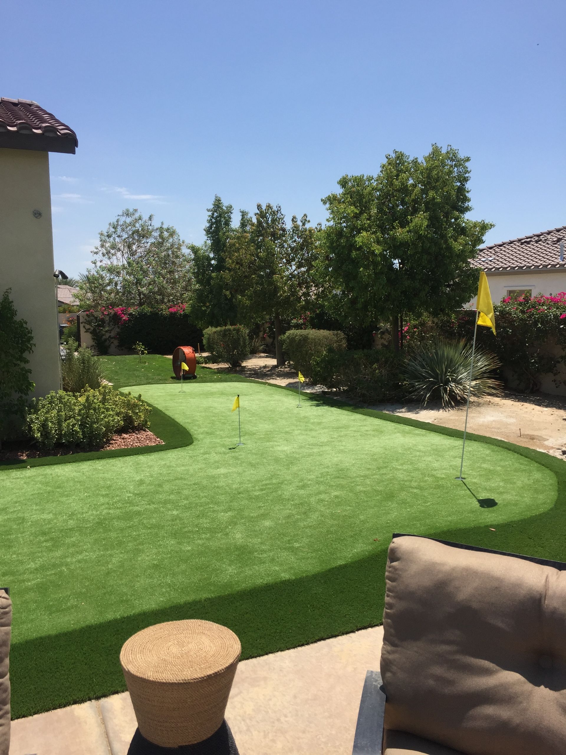 There is a putting green in the backyard of a house.