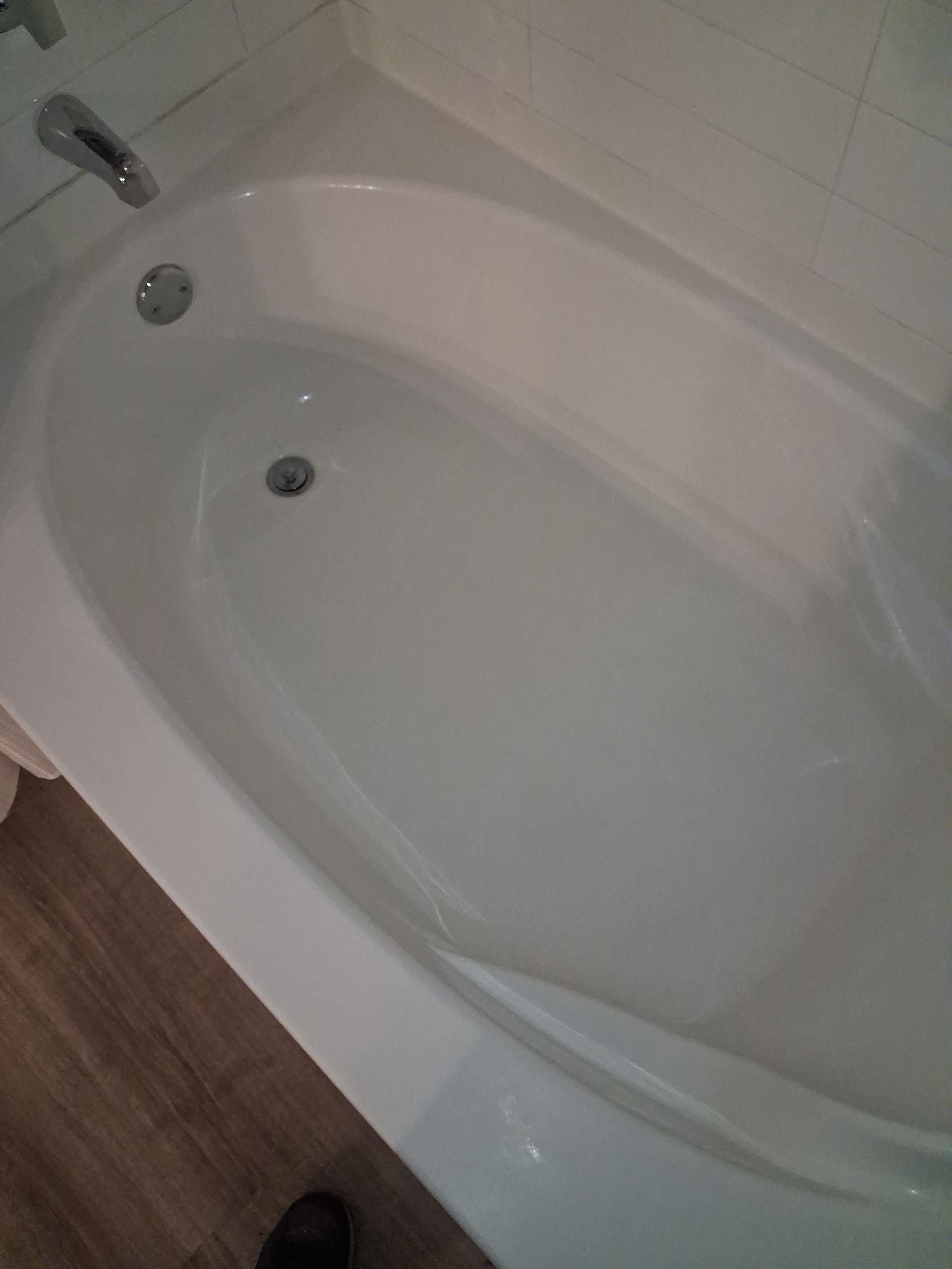 White bathtub with faucet and drain in a bathroom, viewed from above.