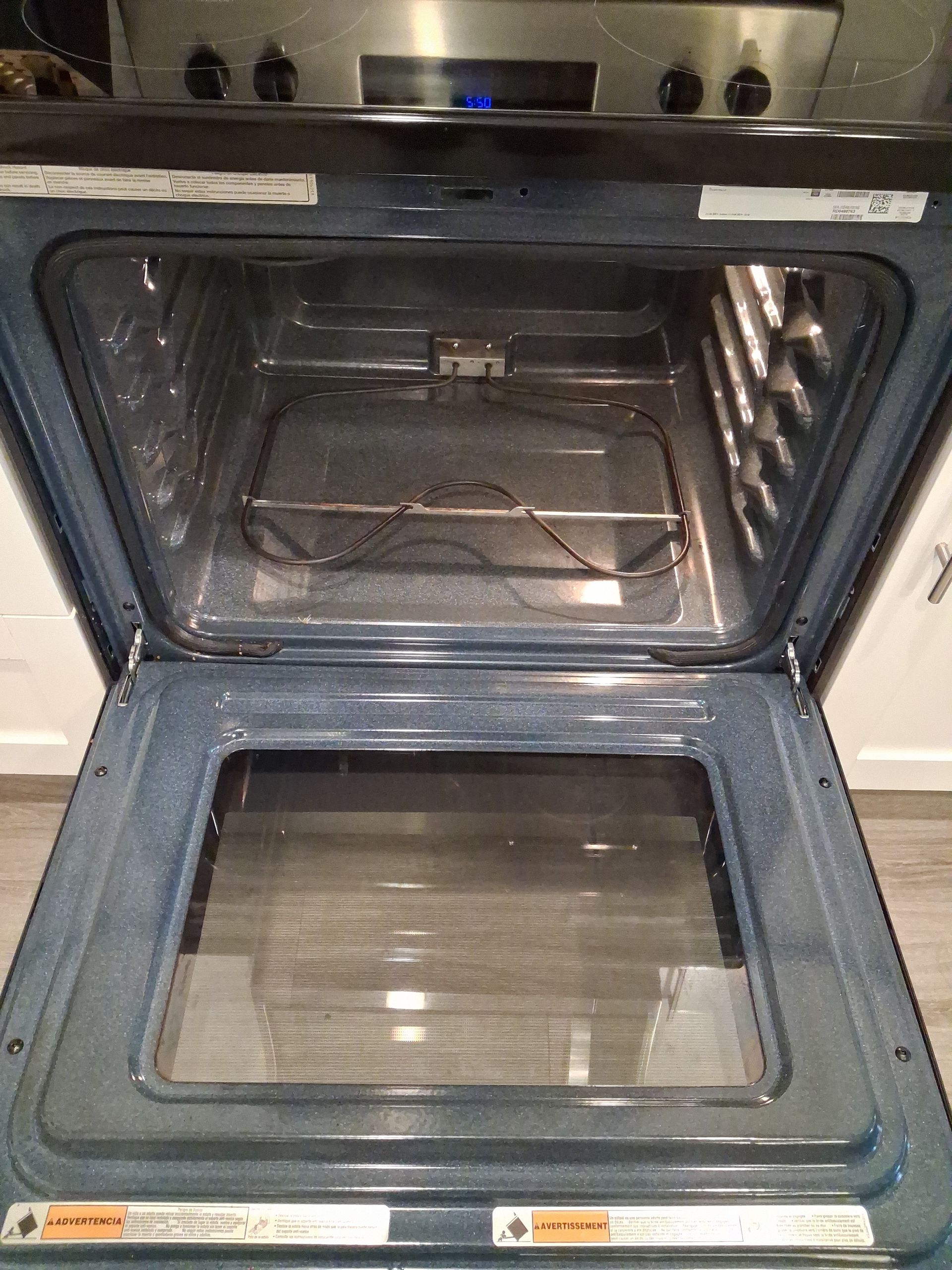 Open oven with stainless steel interior and glass door, viewed from the front.
