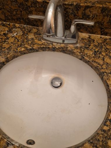 White bathroom sink with chrome faucet on a speckled granite countertop