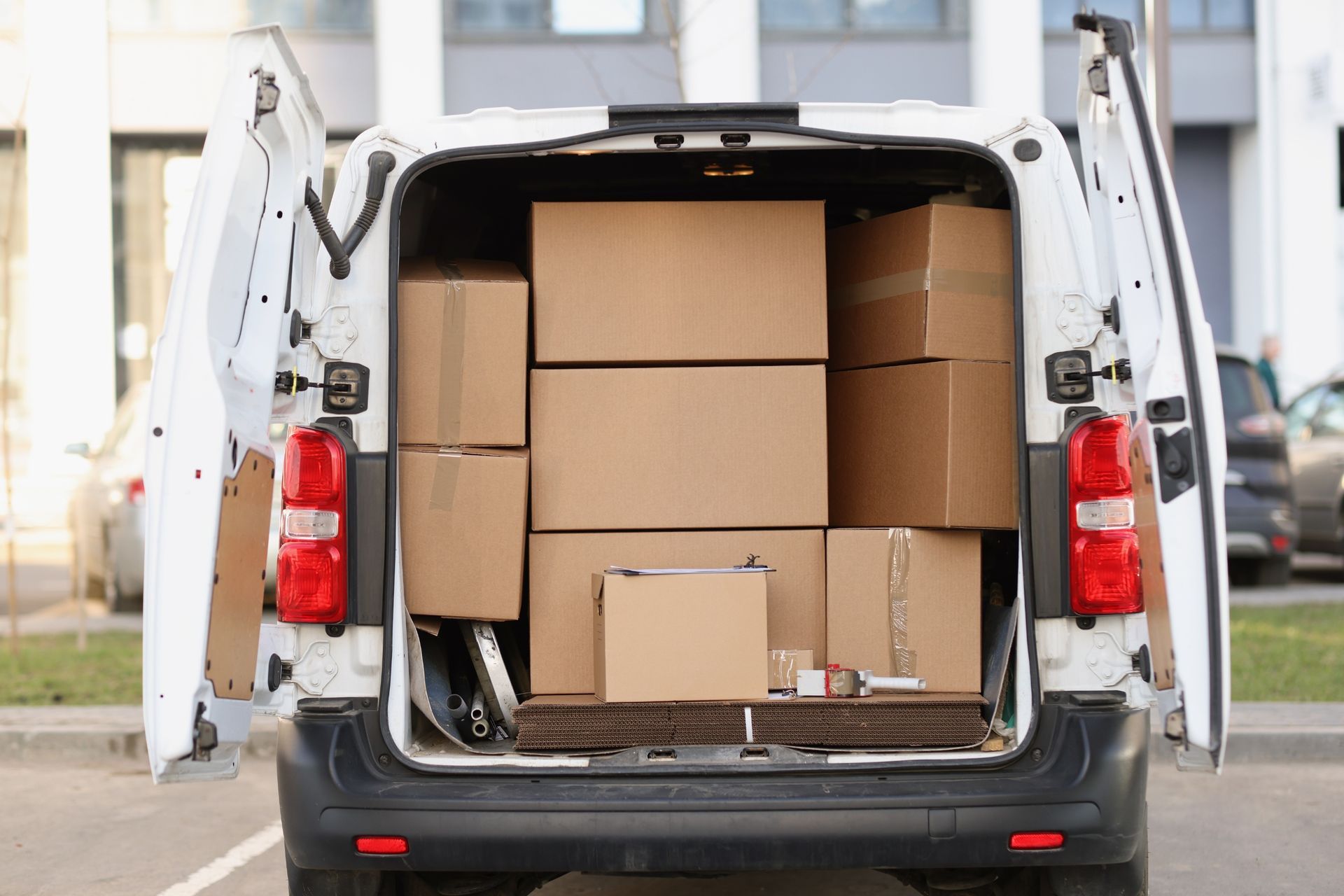 Open van filled with stacked cardboard boxes at a loading area