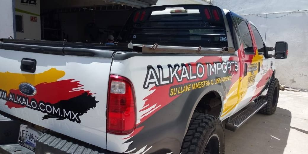 Un camión con una pegatina en la parte trasera que dice Alkalo Imports está estacionado frente a un edificio.