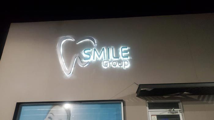 Un letrero de neón en el costado de un edificio que dice grupo de sonrisas.