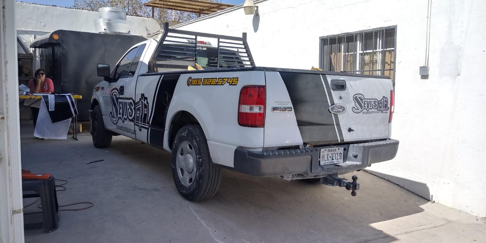 Un camión blanco está estacionado frente a un edificio blanco.