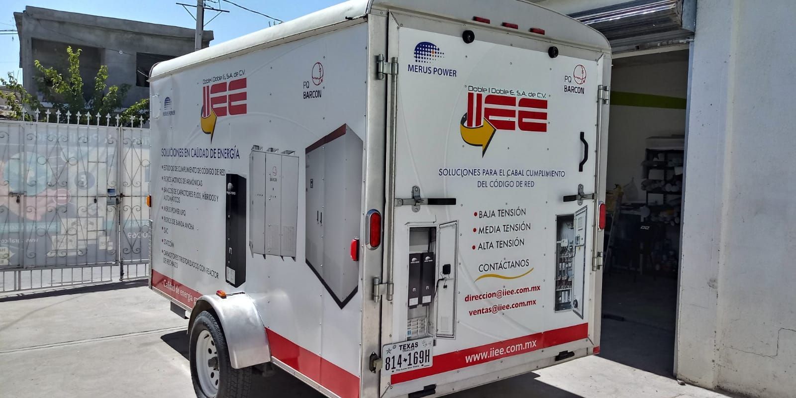 Un remolque blanco y rojo está estacionado frente a un edificio.