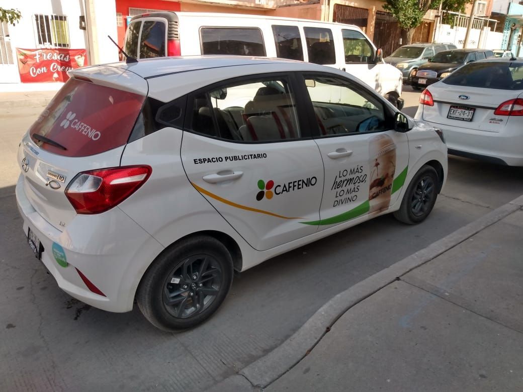 Un coche blanco está aparcado al costado de la carretera.
