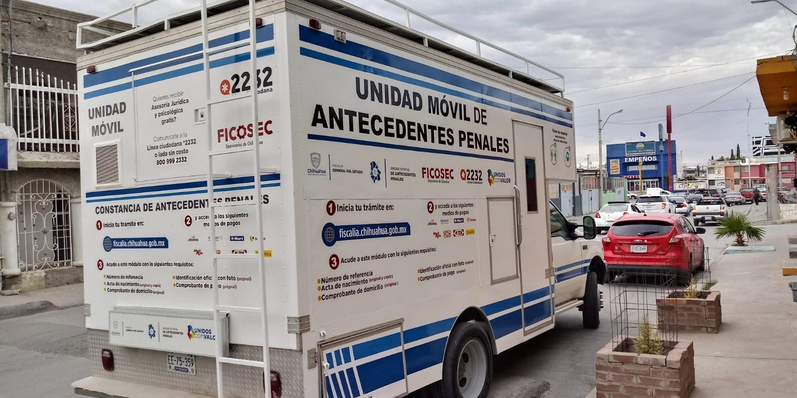 Un camión blanco y azul está estacionado al costado de la carretera.